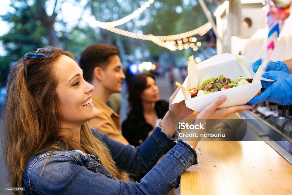 Shot of group of attractive young friends choosing and buying different types of fast food in eat market in the street.