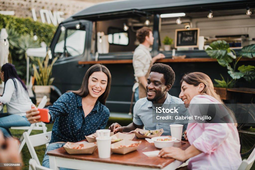 Multiracial people having fun doing selfie at food truck outdoor - Focus on african man face